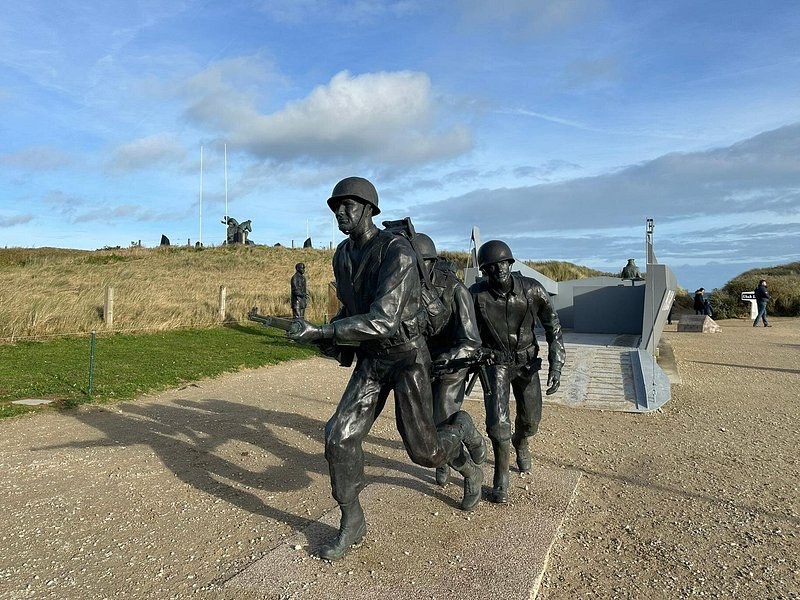 A bronze group of soldiers running up the dunes from a landing craft