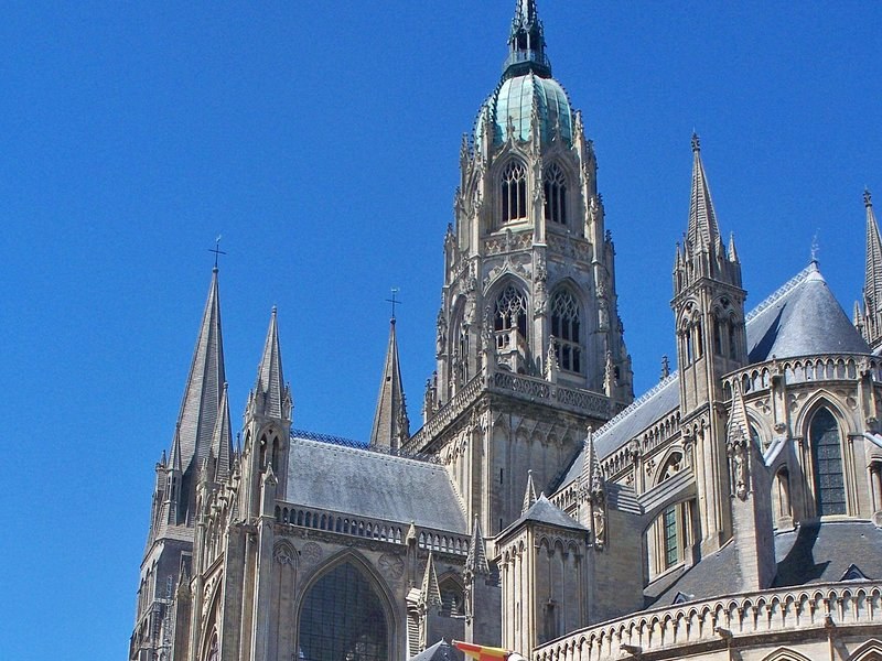 The Gothic spires and central tower of the cathedral in Bayeux against a blue sky