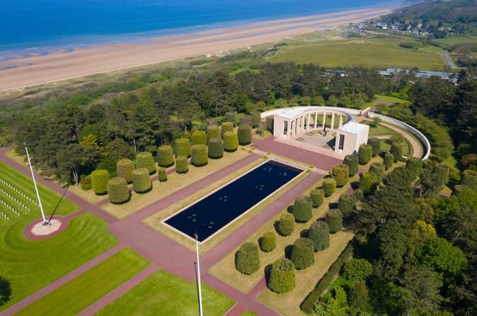 The memorial, its reflecting pool and clipped trees above the long sand of Omaha Beach