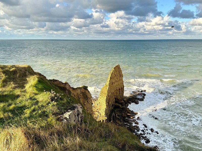 A pinnacle of rock standing off a grassy clifftop above the Channel